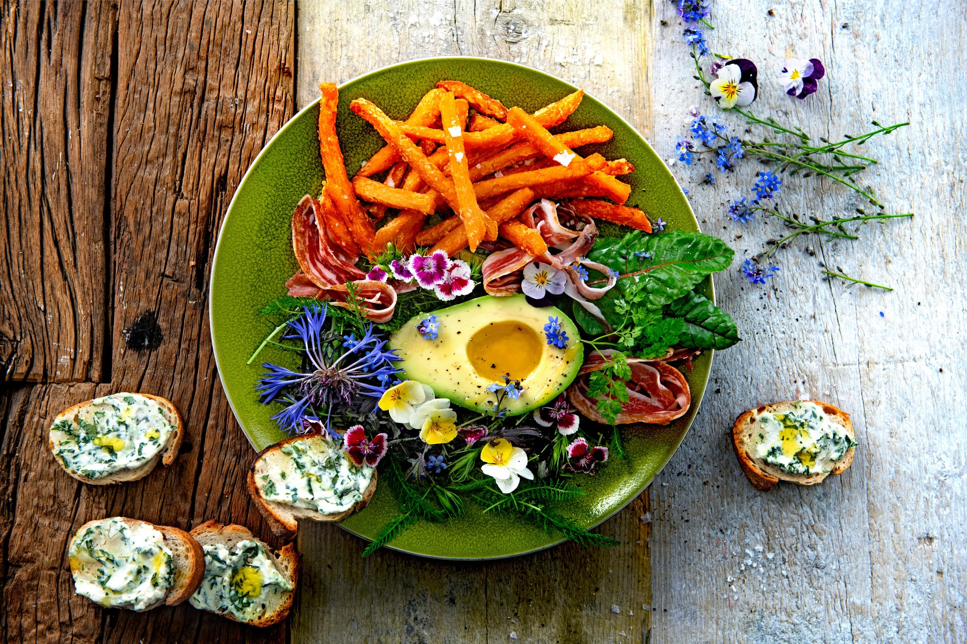 Avocado Blütensalat mit Süsskartoffel-Pommes auf Holztisch serviert